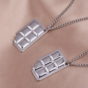 Detailed view of silver chocolate bar pendants with bite marks on satin silk