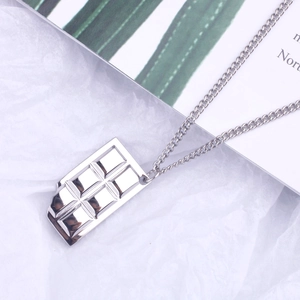 Macro detail of silver chocolate bar pendant with bite mark on high-polished steel chain