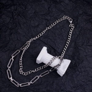 Detail of double-layer titanium necklace with curb and paperclip chains on stone