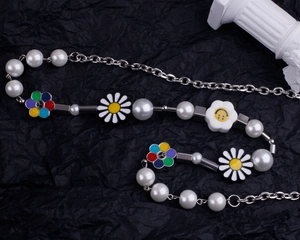Détail du collier de perles avec marguerites et breloques en émail coloré