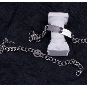 Detail view of silver Cuban chain bracelets with Serendipity plaque and smiley face charm