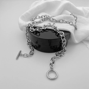 Detail of chunky silver toggle clasp chain necklace on white textured fabric background