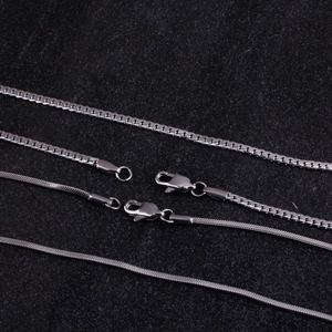 Macro shot of silver titanium steel snake and cuban link necklaces with lobster clasps