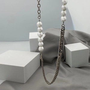 Detailansicht der Perlenkette mit Edelstahl-Cuban-Kette auf minimalistischem Grund