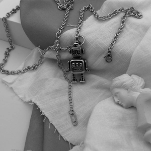 Macro shot of silver robot pendant and O-chain necklace with engraved K18 tag
