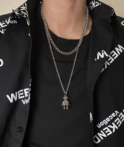 Close-up of layered Cuban link chain with a vintage silver robot pendant necklace