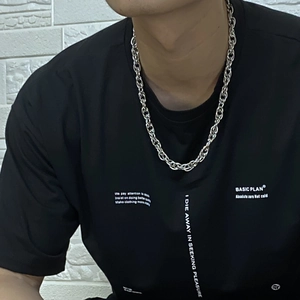 Close-up detail of silver chunky twist chain necklace worn over a black t-shirt