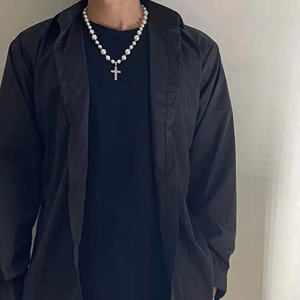 Close-up of pearl necklace with silver cross pendant on a male model wearing black shirt