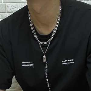 Collier double épaisseur chaîne cubaine argentée avec pendentif rectangulaire sur t-shirt noir