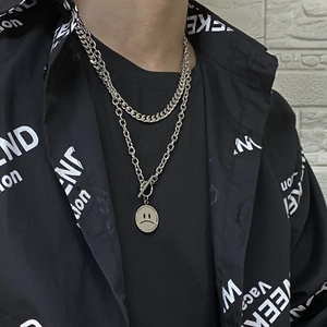 Detail view of double-layered titanium steel cuban chain necklace with a sad face pendant