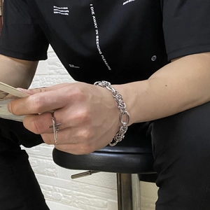 Close-up of titanium steel chain bracelet and cross pendant ring set on male model