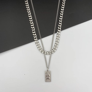 Détail d'un collier double épaisseur argenté avec chaîne cubaine et pendentif carré