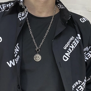 Close-up of a trendy silver spinning smile pendant necklace with OT toggle clasp on model