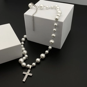 Hip hop pearl necklace with a rhinestone-studded silver cross pendant on a black background