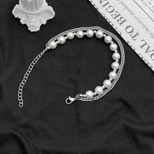 Bracelet double rang avec perles et chaîne argentée sur fond en tissu noir minimaliste