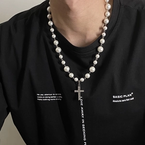 Detail shot of a retro pearl necklace with a shimmering rhinestone cross pendant