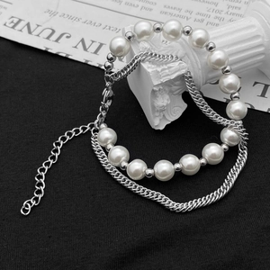 Détail du bracelet double couche en perles et chaîne cubaine argentée sur fond vintage