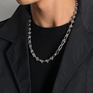 Dettaglio della collana a catena d'argento con nodi indossata da un modello in nero