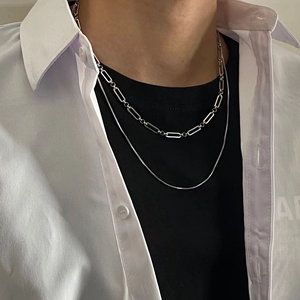 Detail of silver double-layered necklace with paperclip and snake chain on a male model