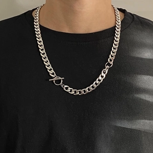 Close-up of a chunky silver Cuban link necklace with a stylish toggle clasp on a black shirt