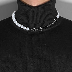 Detail einer Perlenkette mit silbernen Sternengliedern auf einem schwarzen Rollkragenpullover
