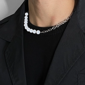 Gros plan d'un collier de perles lumineuses et chaîne argentée sur un blazer noir