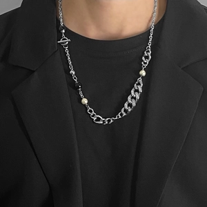 Detail of silver chain necklace with pearls and toggle clasp worn on a black suit