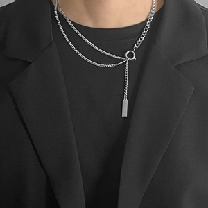 Dettaglio della collana a strati in acciaio al titanio con ciondolo rettangolare su abito nero