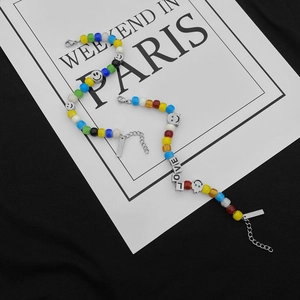 Détail de perles colorées, cubes de lettres LOVE et breloques smiley sur une chaîne
