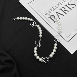 Détail du collier papillon en perles avec fermoir mousqueton sur tissu noir élégant