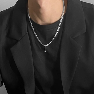 Détail d'un collier chaîne cubaine en acier argenté avec pendentif sphère sur le mannequin