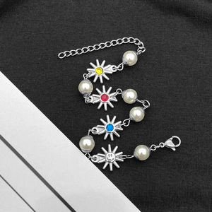 Bracciale in acciaio al titanio con pendenti a sole in pietre colorate e perle su superficie