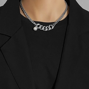 Detail showing hip-hop cuban chain with pavé diamonds and a white pearl charm