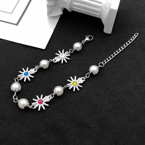 Dettaglio del bracciale in acciaio al titanio con ciondoli a girasole sorridente e perle