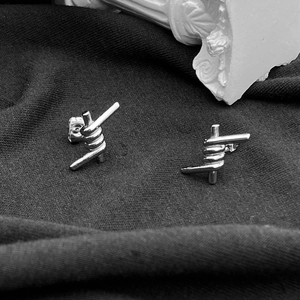 Macro detail of silver stainless steel thorn wire stud earrings for men and women