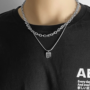 Gros plan d'un collier à chaînes argentées superposées avec un petit pendentif rectangulaire