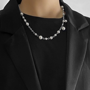 Detail of silver chain and white pearl necklace on model wearing a black blazer
