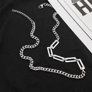 Detailed view of silver Cuban link necklace with geometric stitching on black fabric