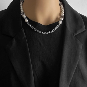 Detalle de la asimetría de perlas y cubos de acrílico en un collar de cadena de acero