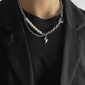 Détail du collier de perles hip-hop avec pendentif cœur porté sur un costume noir chic