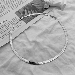 Chaîne serpent plate blanc argenté minimaliste avec fermoir mousqueton sur tissu blanc