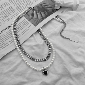Dettaglio della collana a doppio strato con perle, catena cubana e ciondolo a cuore