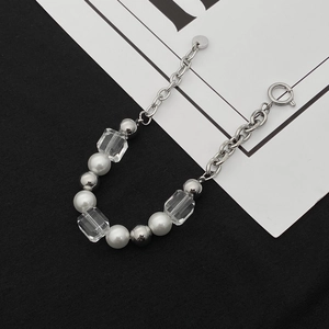 Détail de la chaîne en acier titane avec perles blanches et cube en cristal clair