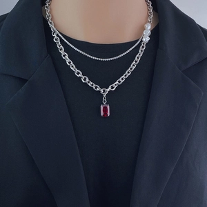 Close-up of hip hop layered necklace with a red gemstone pendant and silver link chain