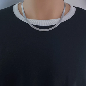 Vue détaillée du collier en maille serpent argentée sur le cou du mannequin style hip hop