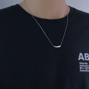 Close-up of a minimalist silver snake bone necklace with a polished curved tube pendant