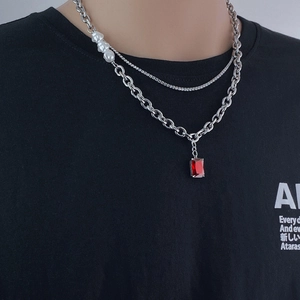 Double-layered punk necklace with ruby pendant and pearls over a black shirt
