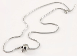 Close-up of vintage silver skull pendant on snake chain with black stone eyes details