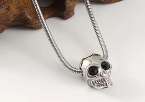 Close-up of gothic silver skull pendant with black gem eyes on a sleek snake chain
