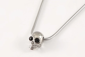 Detailed macro view of retro skull pendant with black zircon eyes on snake chain